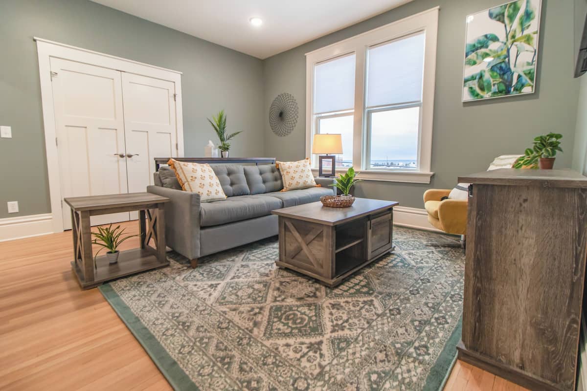 A living room with a grey sofa, a coffee table, and a patterned rug.