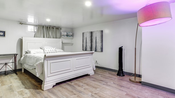 A bedroom with a white bed, a standing lamp, and a floor lamp.