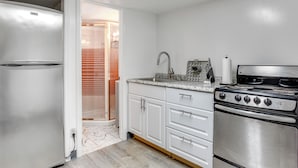 A kitchen with a stainless steel refrigerator, a stove, and white cabinets.