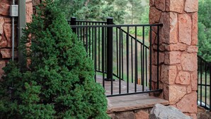 A stone structure with a wooden roof, a metal railing, and a view of a mountainous landscape. - Private Family Home: Spacious Patio, Hot Tub, Fire Pit by Forest & Peak Retreats (Cascade-Chipita Park)