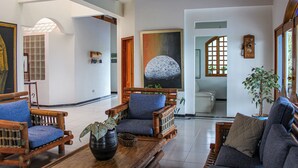 A spacious lobby with wooden furniture, a large painting, and a potted plant. - Hacienda siete sentidos  (La Mesa)
