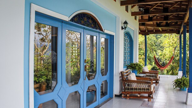 A covered porch with blue doors, wooden benches, and potted plants. - Hacienda siete sentidos  (La Mesa)