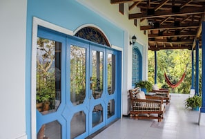 A covered porch with blue doors, wooden benches, and potted plants. - Hacienda siete sentidos  (La Mesa)