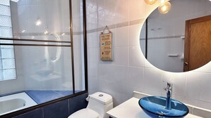 A modern bathroom with a white toilet, a blue sink, and a large mirror. - Hacienda siete sentidos  (La Mesa)