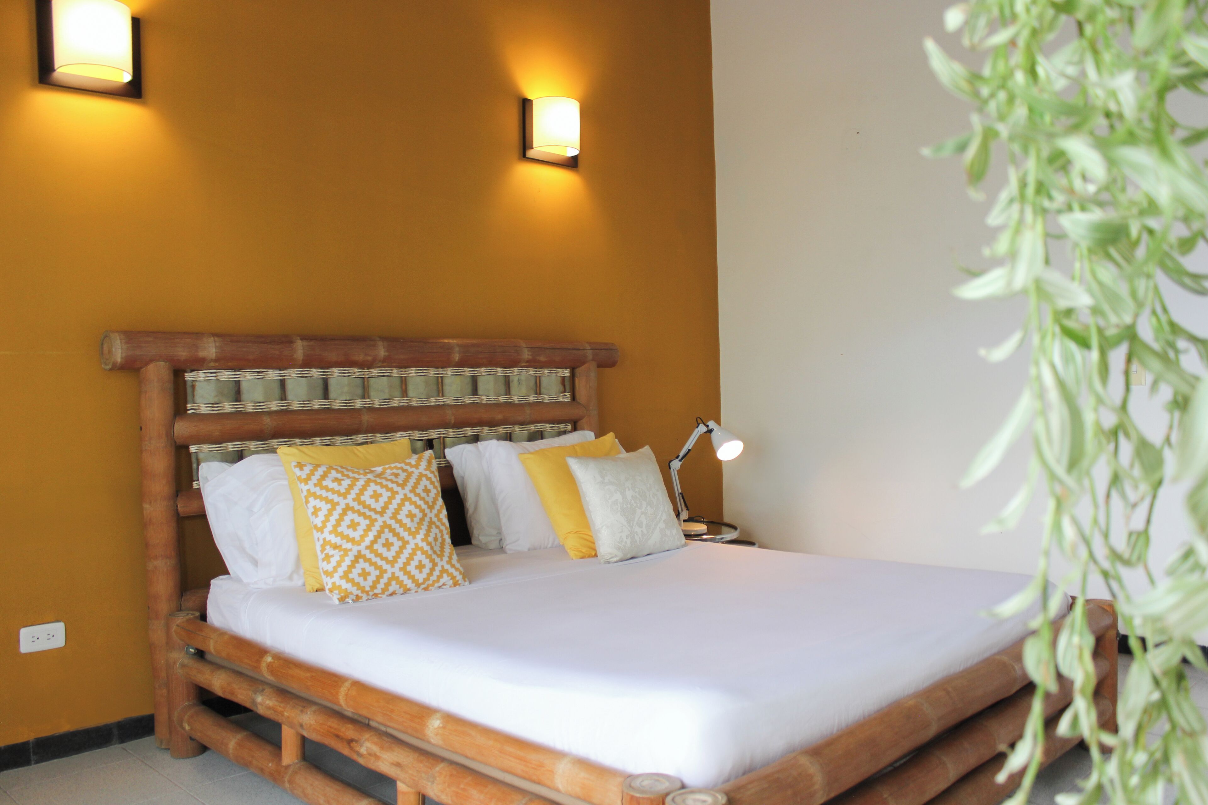 A bed with a wooden headboard, two wall-mounted lights, and a bedside lamp.