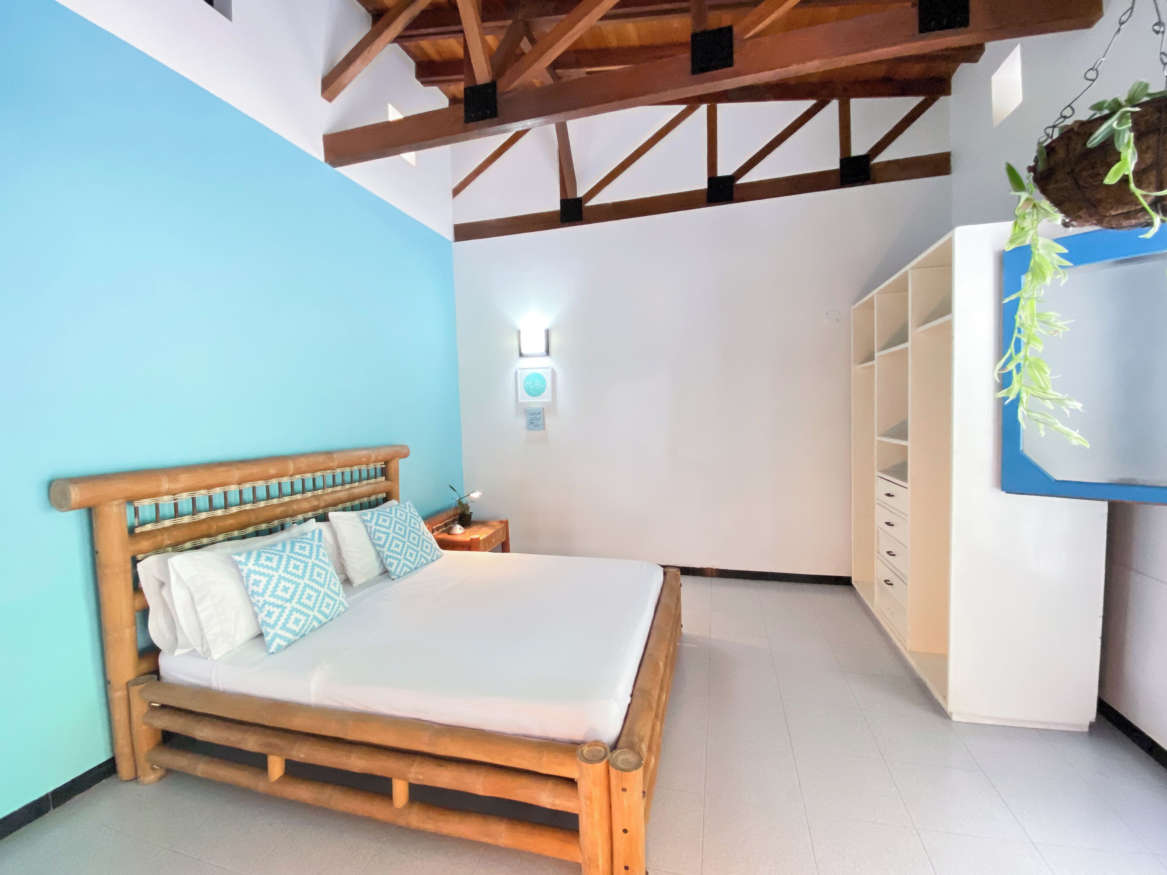 A bedroom with a wooden bed, a nightstand, a wall-mounted light, and a white wardrobe.
