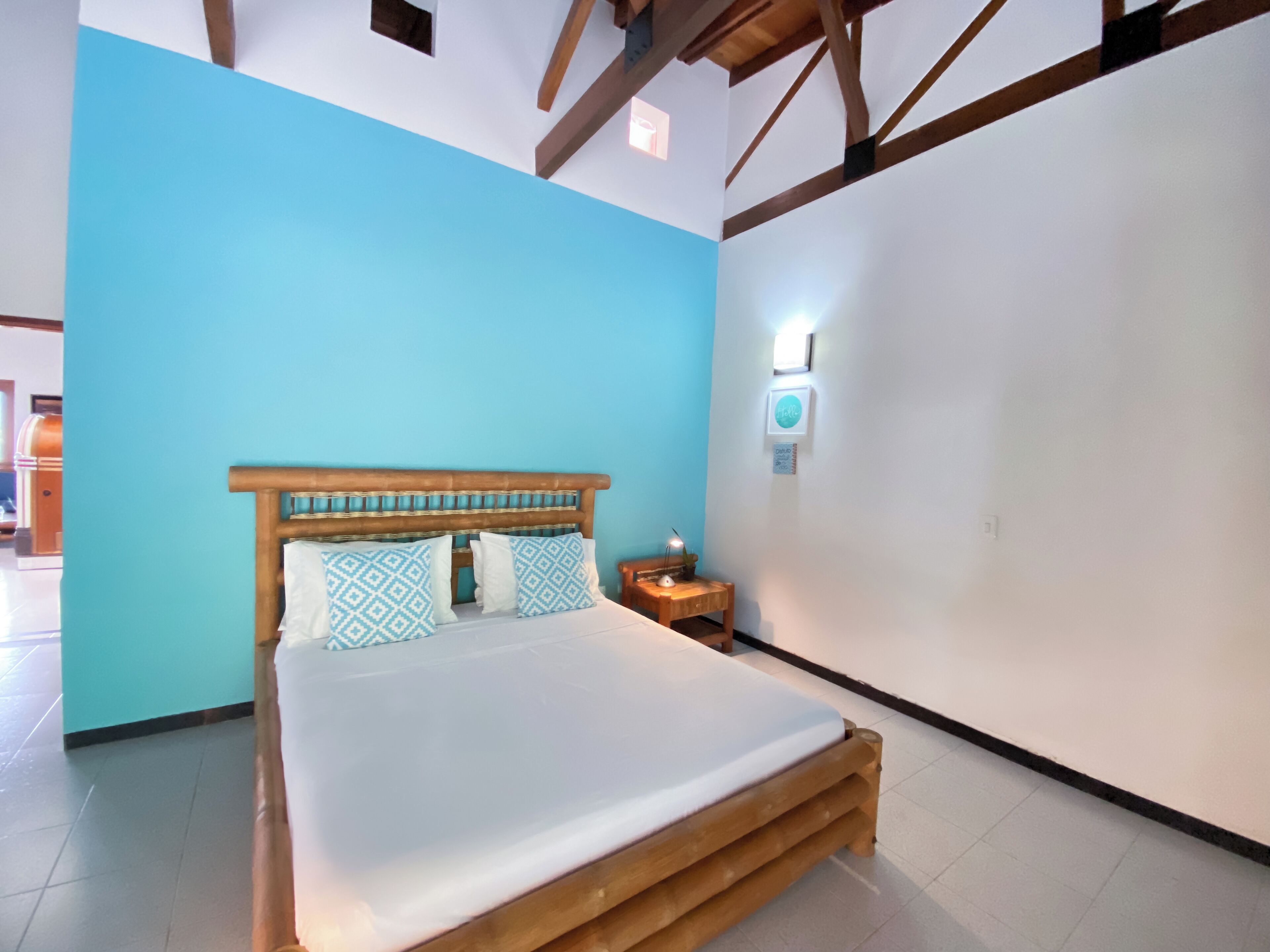 A bedroom with a wooden bed, blue walls, and a nightstand with a lamp.