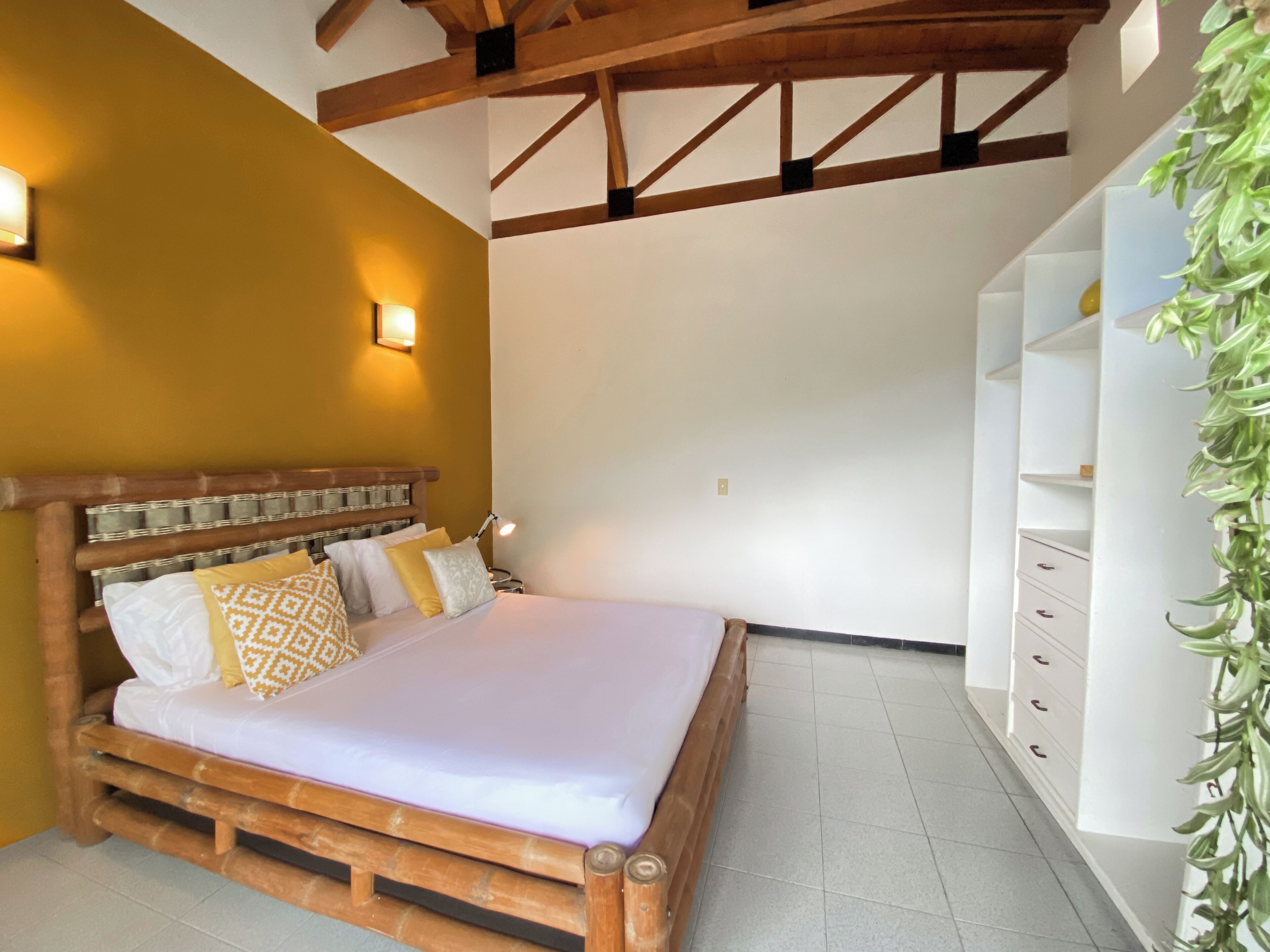 Une chambre à coucher avec un lit en bois, des murs blancs et une armoire blanche.