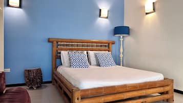 Una cama con estructura de madera, dos almohadas, una lámpara de noche y una lámpara de pared.