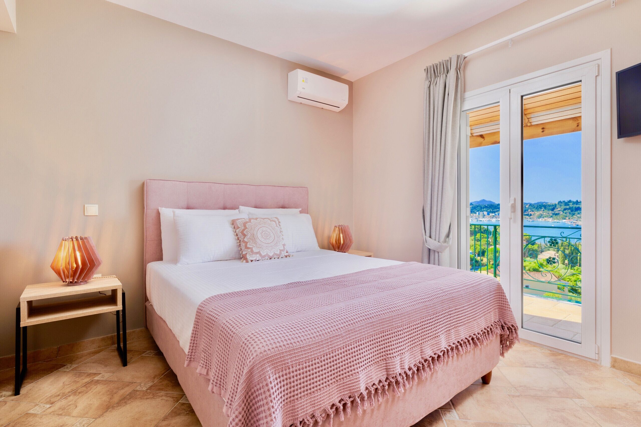 Une chambre avec un lit, une table de chevet, un appareil de climatisation et un balcon avec vue.