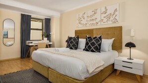 A modern bedroom with a large bed, a desk, and a nightstand. - Elegant 1 Bedroom Loft - Soho on Rose (Cape Town)