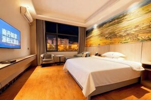 A hotel room with a bed, a desk, a chair, a TV, and a large window.