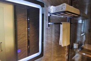 A bathroom with a glass shower enclosure, a towel rack with towels, and a glass cabinet with toiletries. - Nandan Home Inn Paibaiyun Hotel (Nandan)
