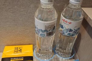 Dos botellas de agua transparentes con etiquetas, un paquete amarillo y una superficie marrón.