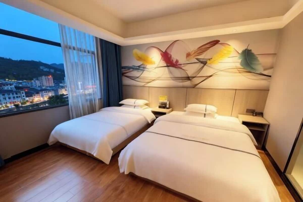 A hotel room with two beds, a city view, and a decorative wall art piece.