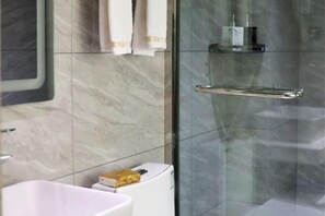 A bathroom with a white sink, a glass shower enclosure, and a towel rack. - Nandan Home Inn Paibaiyun Hotel (Nandan)