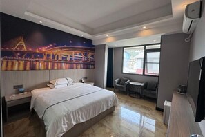 A modern hotel room with a large bed, a nightstand, a desk with a chair, a TV, and a large window with a view of the city. - Nandan Home Inn Paibaiyun Hotel (Nandan)
