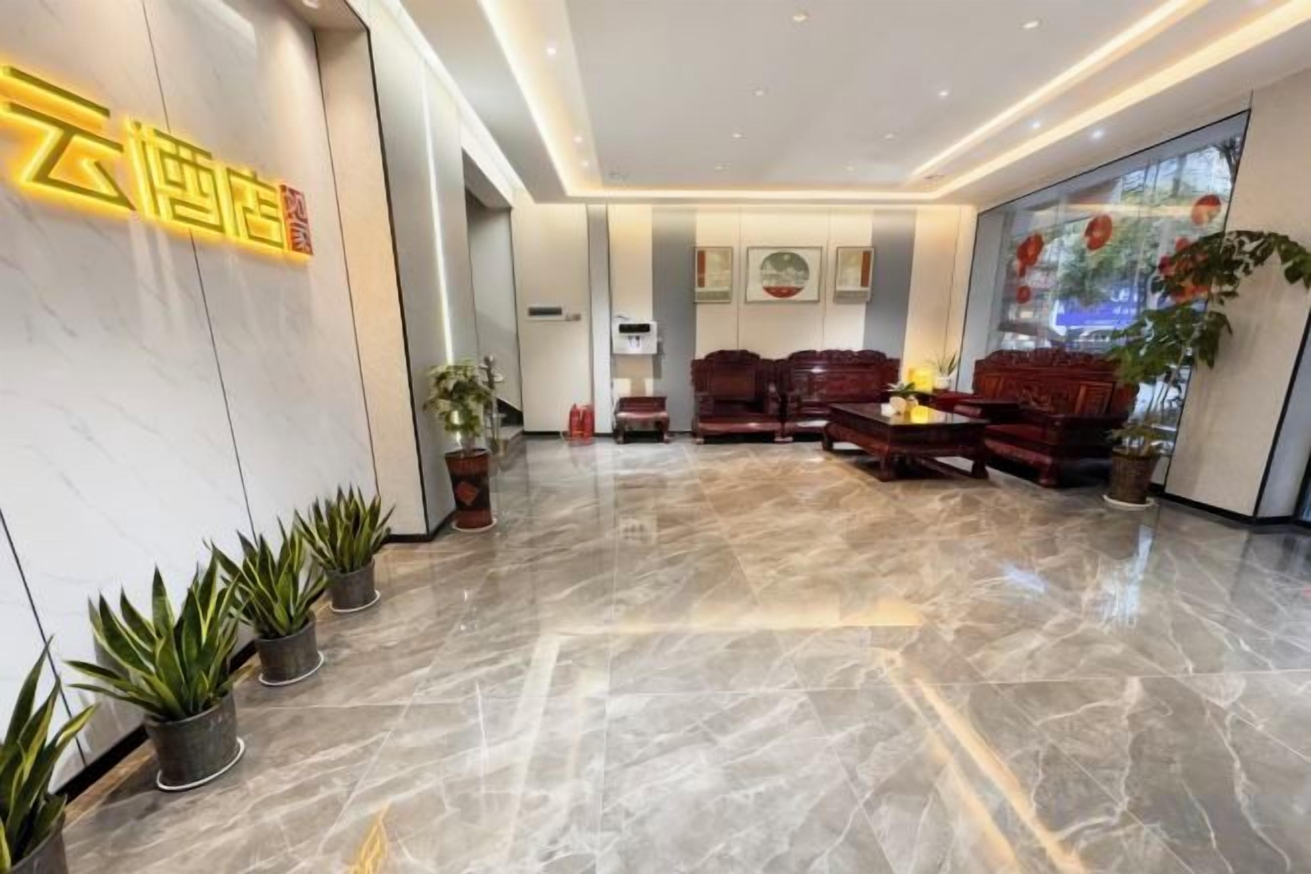 A hotel lobby with a marble floor, seating area, and potted plants.