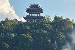 A traditional multi-tiered pagoda-style building surrounded by dense forest. - Nandan Home Inn Paibaiyun Hotel (Nandan)
