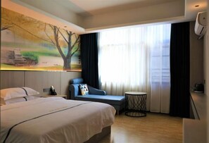 A hotel room with a large bed, a seating area with a view of the city, and a painting on the wall. - Nandan Home Inn Paibaiyun Hotel (Nandan)
