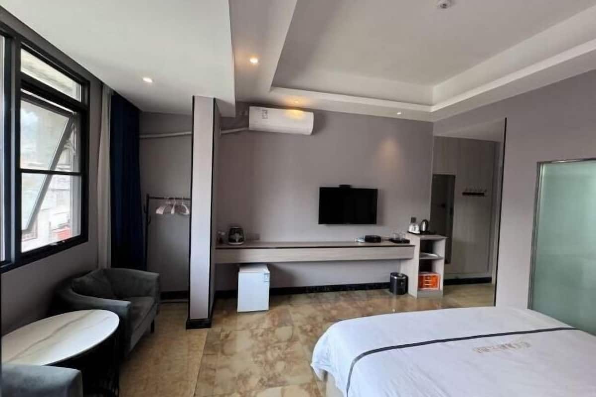A hotel room with a bed, a desk, a chair, a TV, and a window.