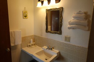Un baño con lavamanos, espejo, toallero e iluminación empotrada.