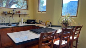 Una cucina con una grande isola, sedie di legno, un forno a microonde e una pianta in vaso.