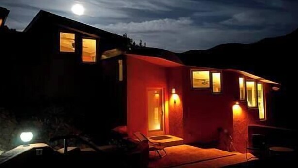 Una casa moderna con facciata rossa, diverse finestre e una porta ben visibile.