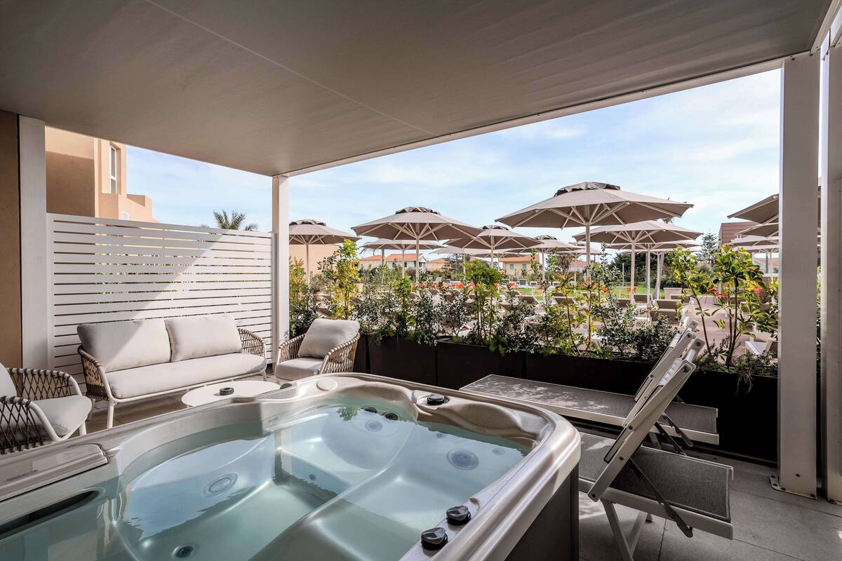 A rooftop terrace with a hot tub, lounge chairs, and umbrellas.