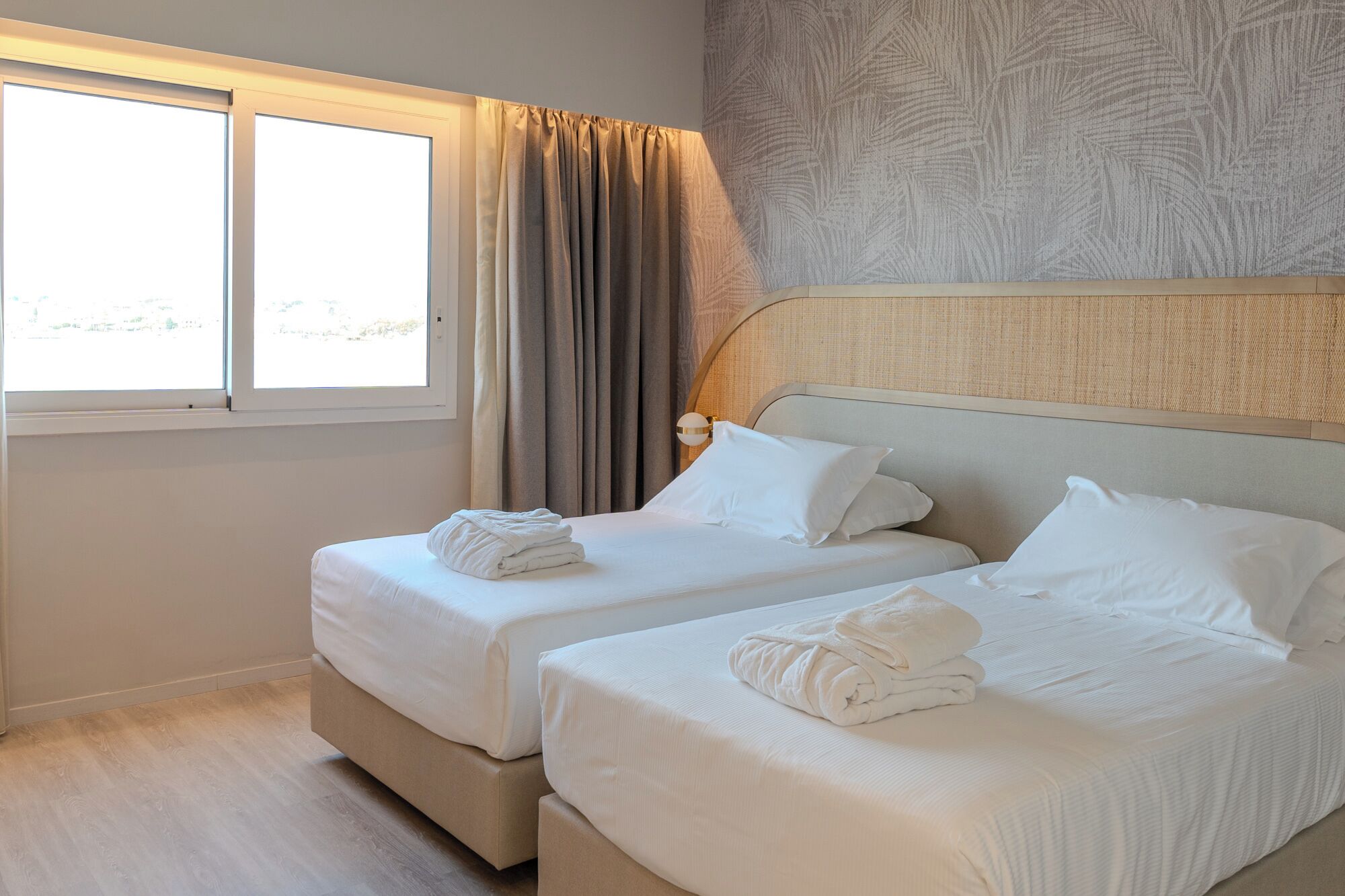 Habitación de hotel con dos camas, una ventana y vistas al exterior.