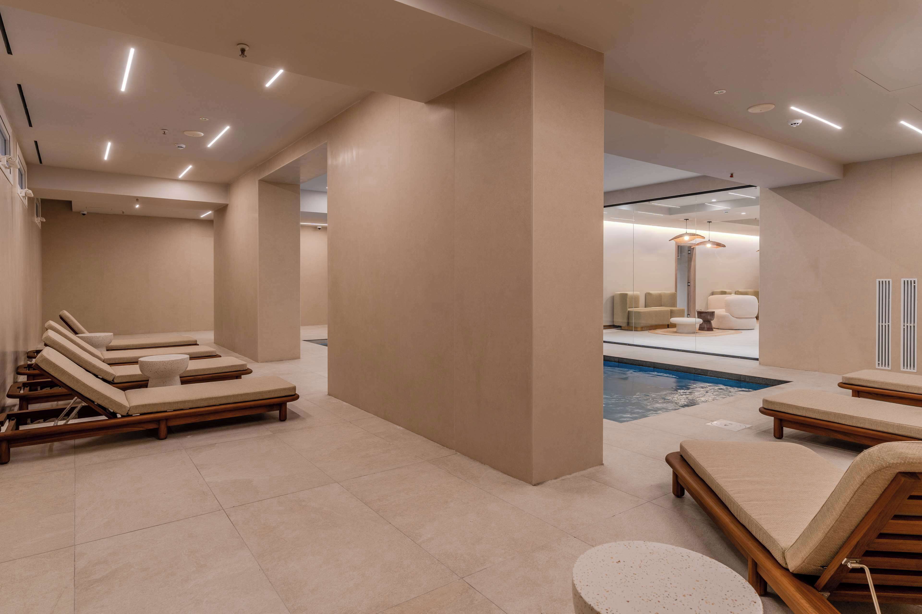 Uma área interna de piscina moderna, com espreguiçadeiras e mesa de bilhar.