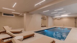 A modern indoor pool area with lounge chairs, a pool, and recessed ceiling lighting. - Terradamari Resort & Spa Marina di Modica, Tapestry by Hilton (Modica)