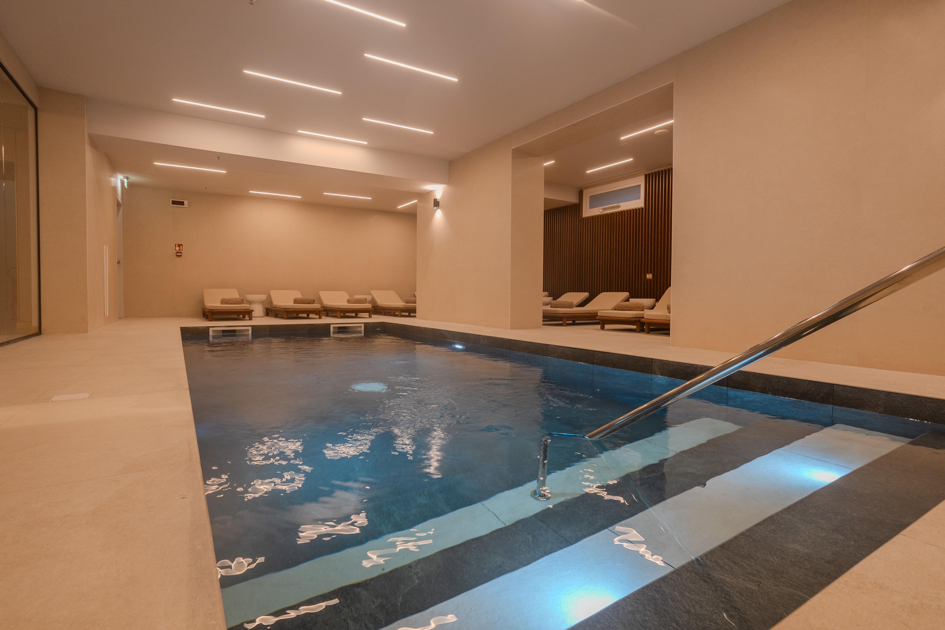 A swimming pool with a clear blue water surface, surrounded by lounge chairs and a staircase leading to a higher level.
