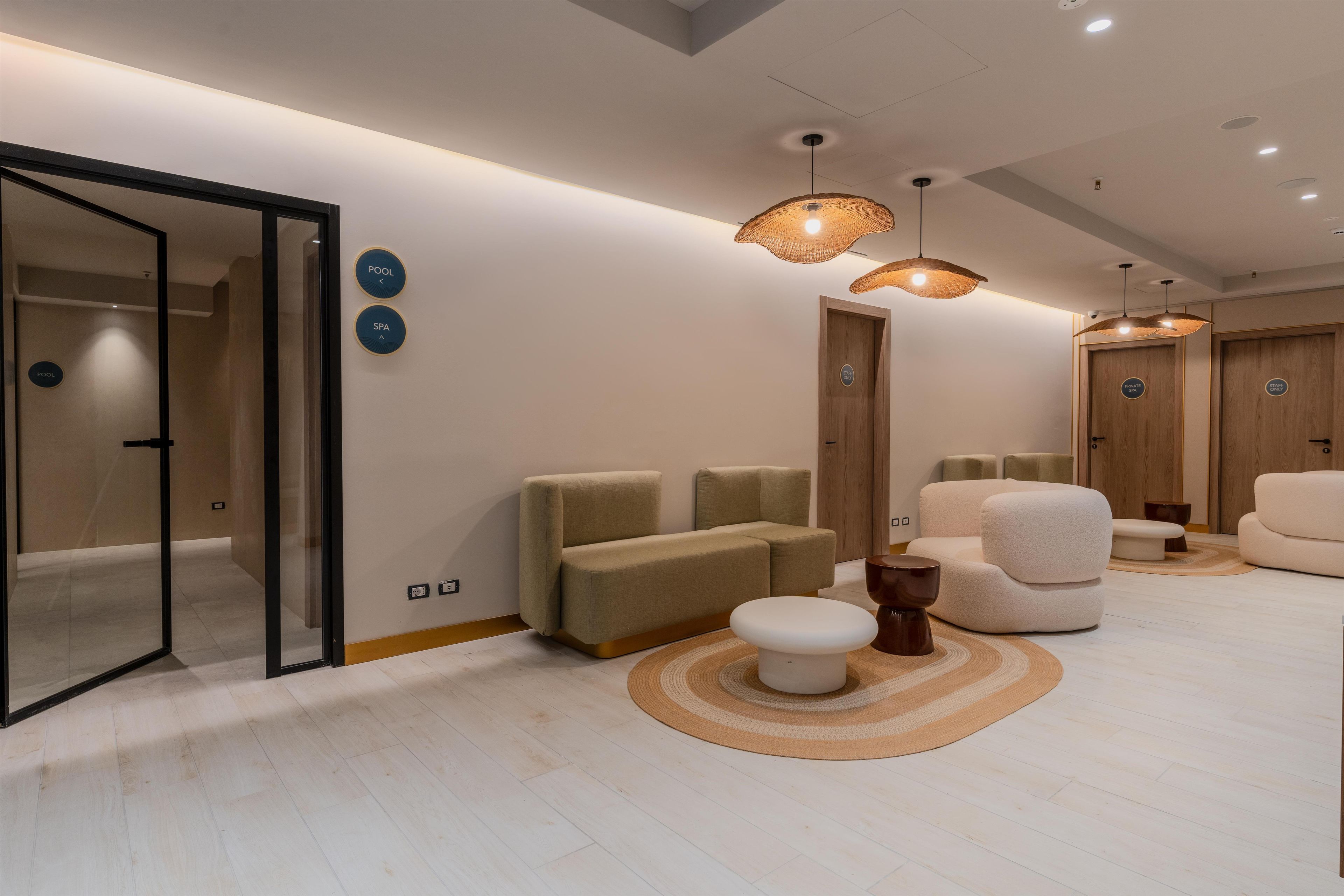 A modern hotel room with a sofa, a small round table, a wooden door, and a glass partition.