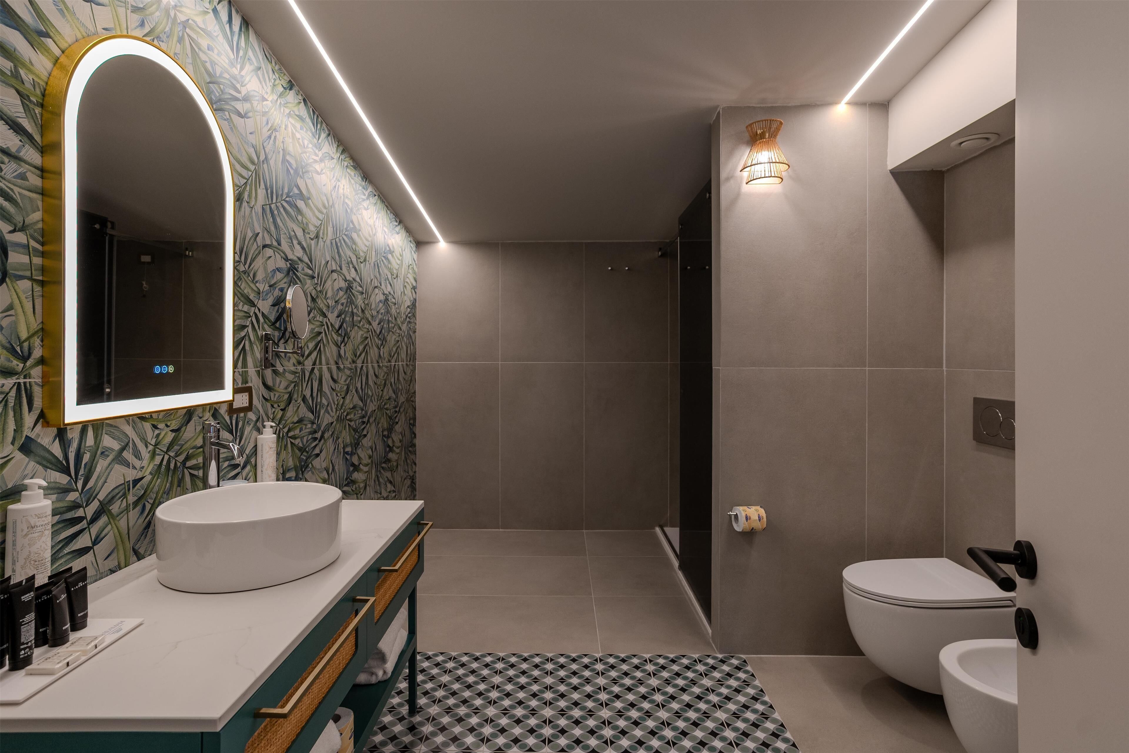 Een moderne badkamer met een grote spiegel, een rond wastafeltje, een toilet en een douche.