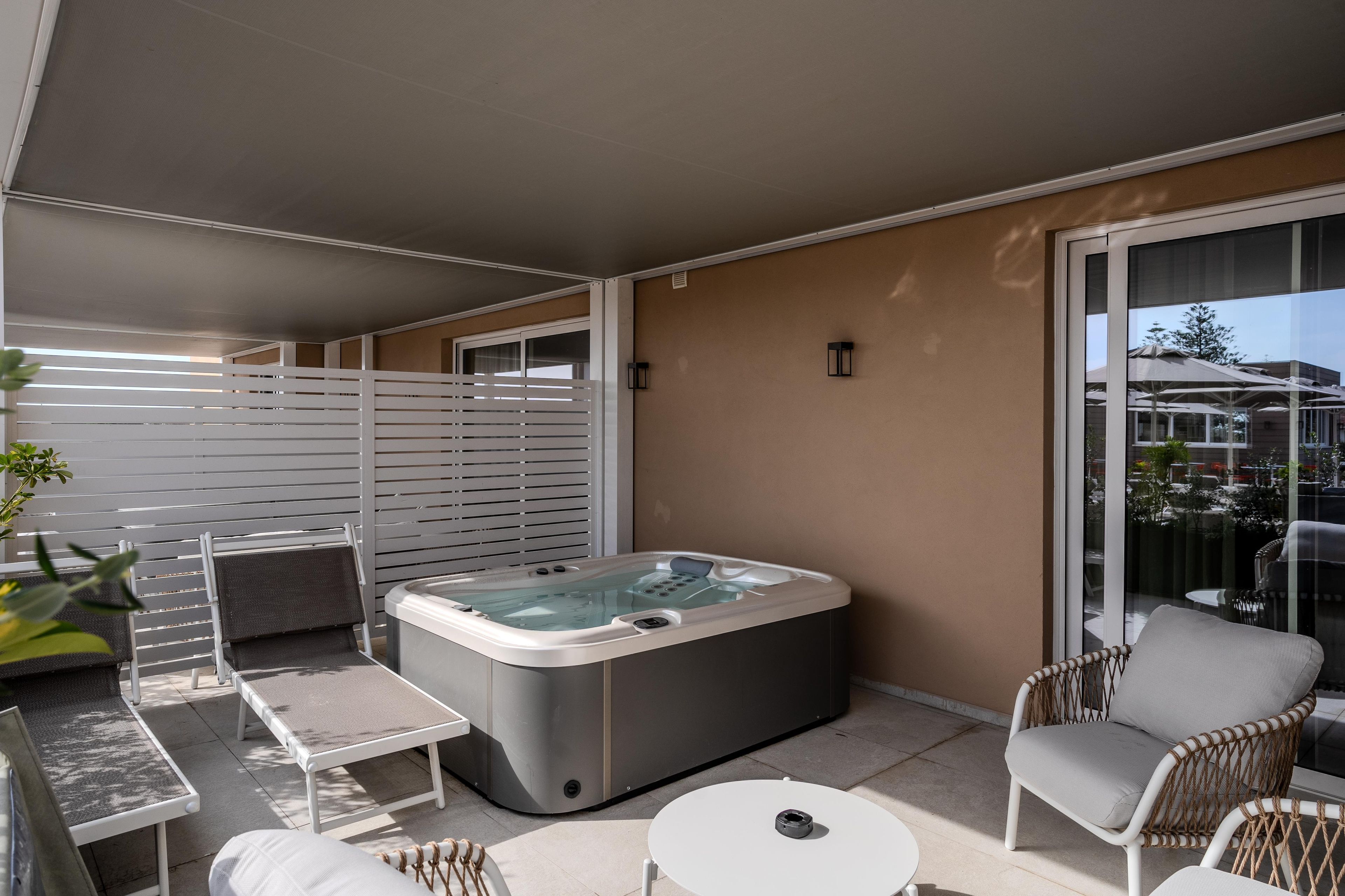 Ein Balkon mit Whirlpool, einem Stuhl, einem Tisch und einem Fenster.