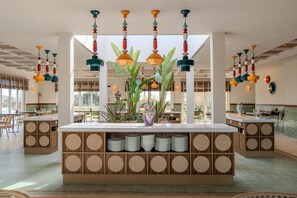 Ein modernes Interieur mit einer zentralen Kücheninsel, mehreren hängenden Pendelleuchten und Blick ins Freie.
