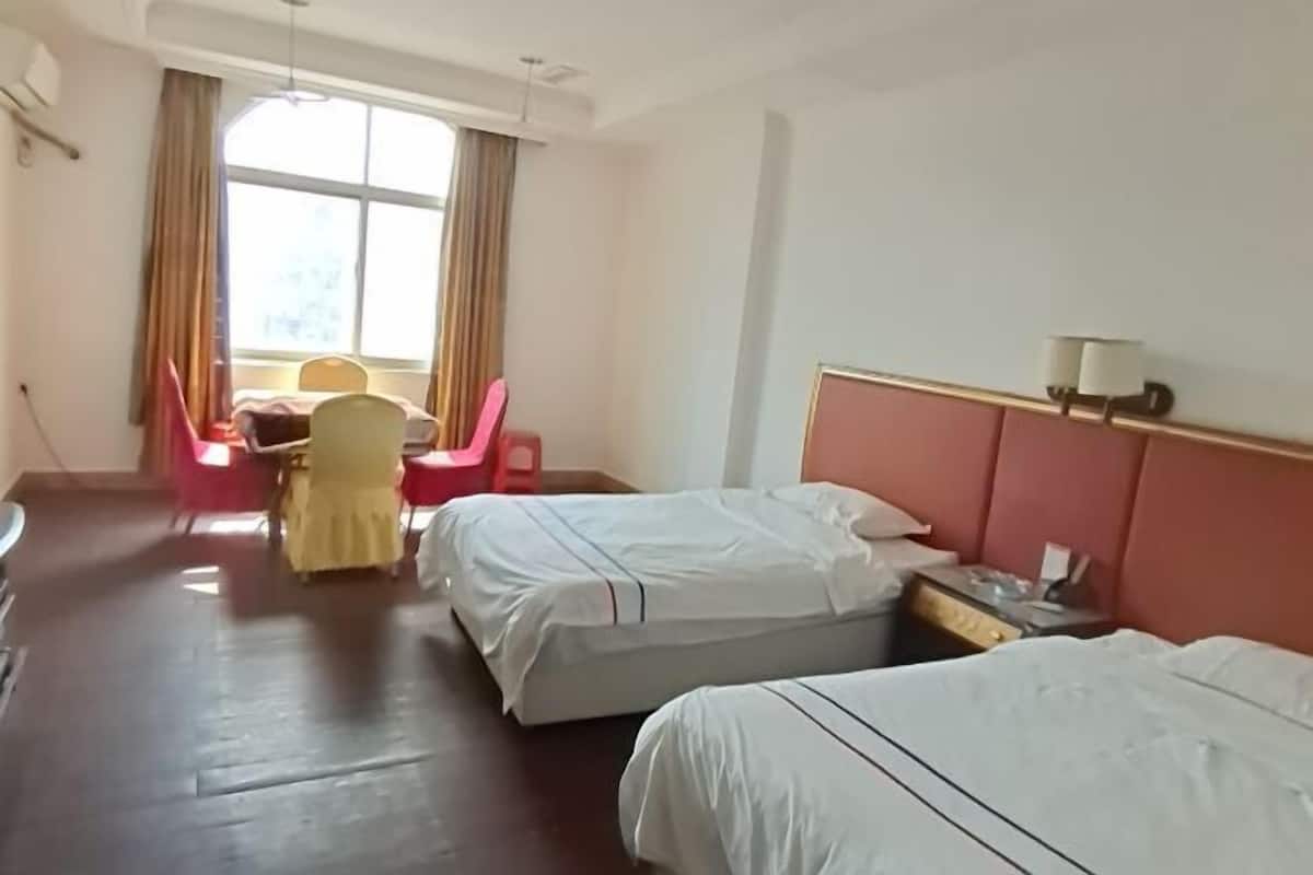 A hotel room with two beds, a desk, a chair, and a window with curtains.
