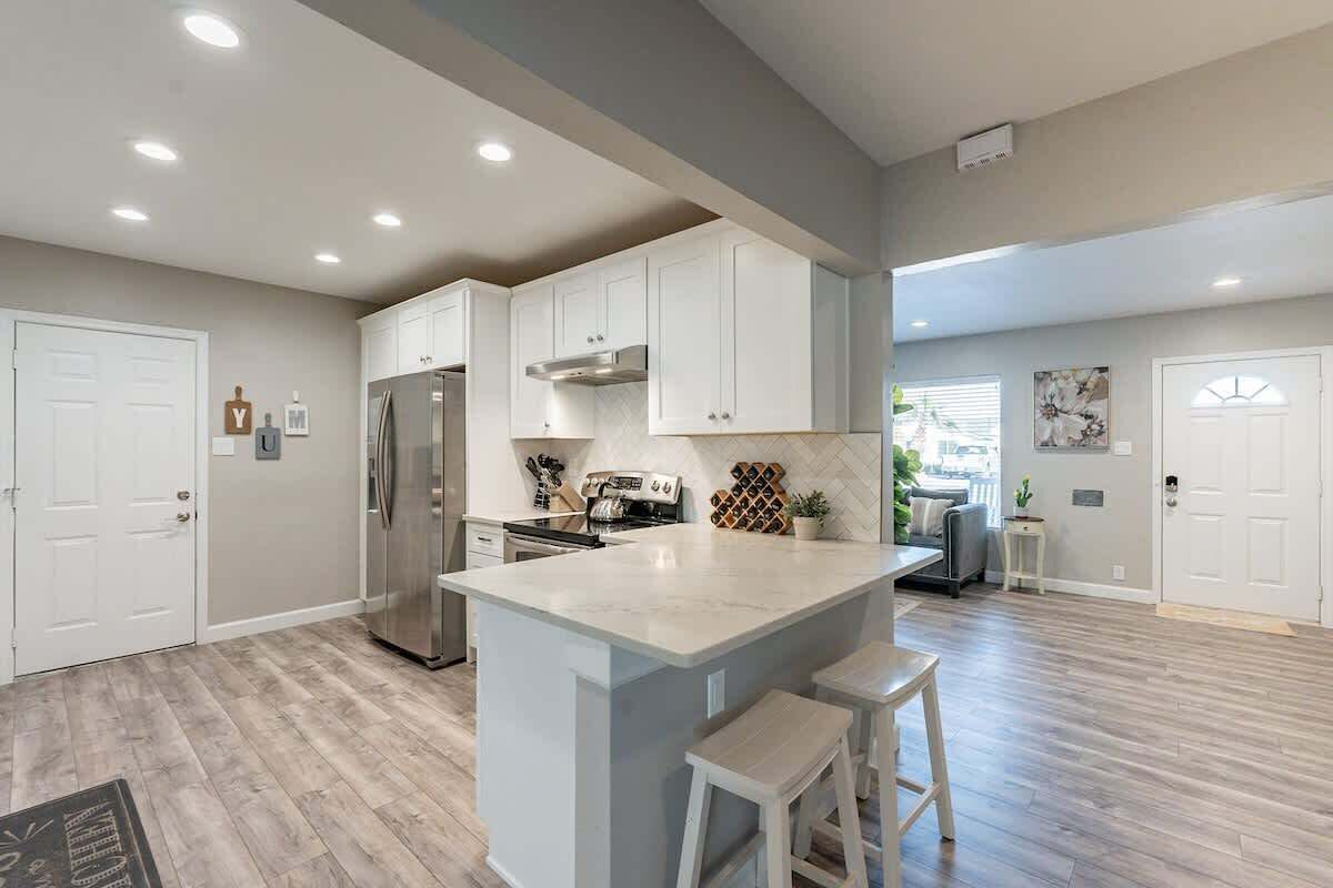 A modern kitchen with white cabinetry, a central island, and a stainless steel refrigerator.