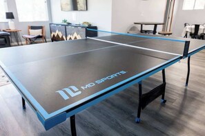 A ping pong table with 'MD Sports' branding, set in a room with a modern design, including a wooden floor and a whiteboard in the background.