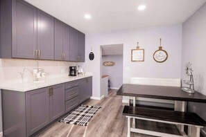 A modern kitchen with grey cabinets, a white countertop, and a dark wooden dining table. - Family Cabin Games & Fire Pit (Payson)