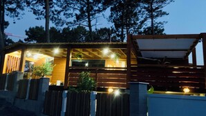 Ett modernt hus med en träfasad, en inglasad veranda och en väl upplyst interiör.