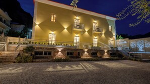 A building with multiple balconies, a stone facade, and a gravel driveway.