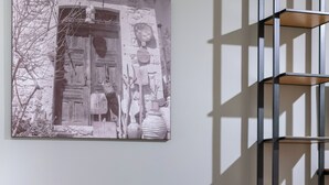 A room with a beige sofa, a black metal shelving unit, and a large monochrome artwork on the wall.