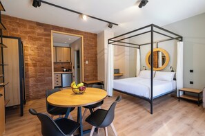 Un dormitorio moderno con cama con dosel, un espejo redondo y un área de comedor con mesa y sillas.