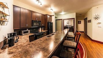 A modern kitchen with dark wooden cabinets, a granite countertop, and a built-in microwave.