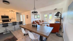 Una cocina moderna con taburetes de bar, una mesa de comedor con sillas e iluminación colgante.
