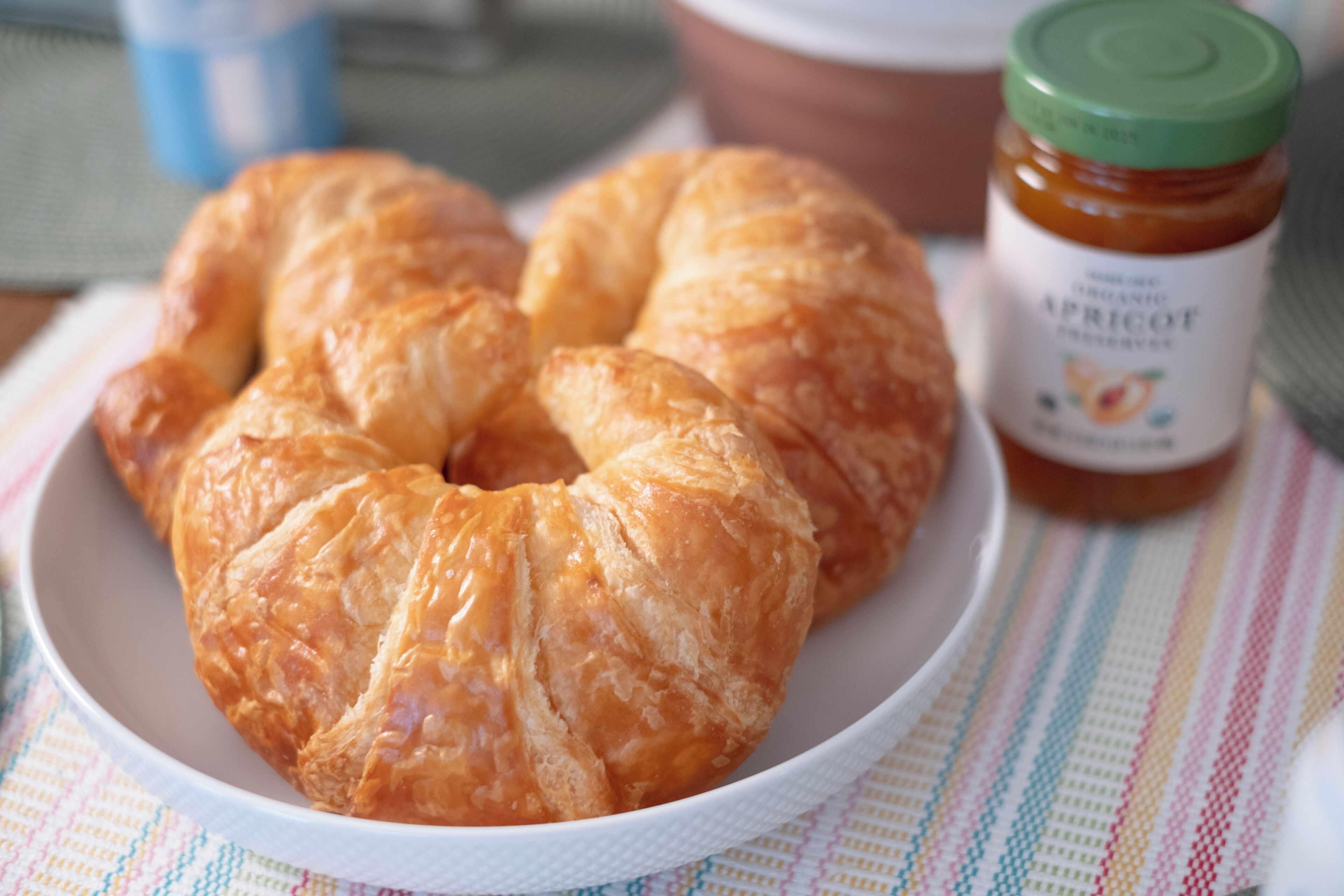 A plate with croissants and a jar of apricot jam.