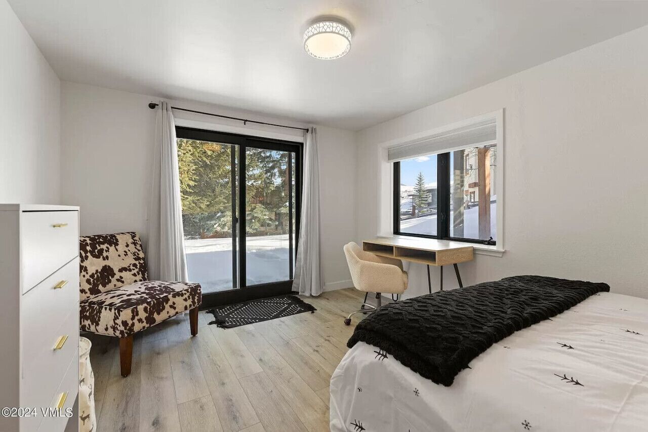 A modern bedroom with a bed, a desk, a chair, and a wardrobe.