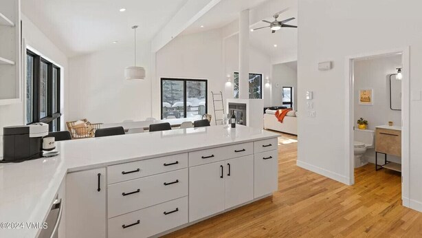 A modern kitchen with a large island, white cabinetry, and a dining area with a table and chairs.